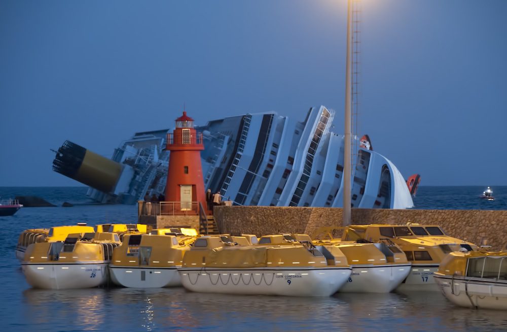 The Costa The lifeboats were moored inside the harbor pier before dawn. The grounded ship sank in background.