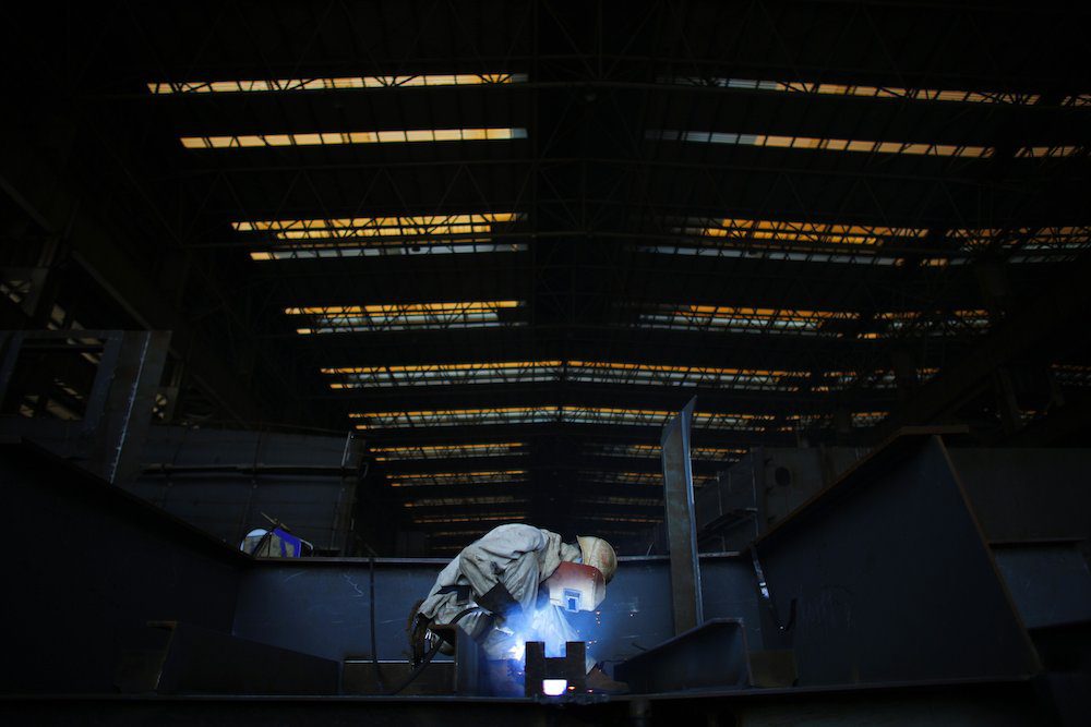 A labourer works on a section of a vessel which is under construction at the Waigaoqiao shipyard in Shanghai November 5, 2013. REUTERS/Carlos Barria