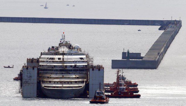 Tugboat maneuver the Costa Concordia towards its berth in the port of Genoa, July 27, 2014. REUTERS/ Stefano Rellandini