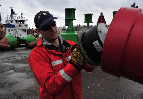 Seaman Zach Beyer, of Coast Guard Buckthorn, removes a battery on a lighted, radar-reflective buoy during routine shoreside maintenance at Coast Guard Sector Sault Ste. Marie. U.S. Coast Guard photo by Petty Officer 1st Class Charles C. Reinhart.
