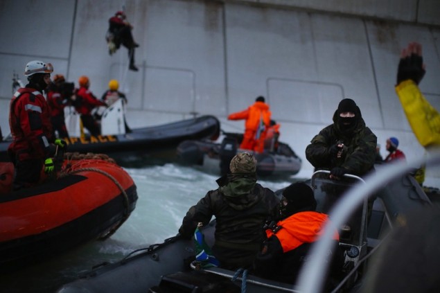 A Russian Coast guard officer is seen pointing a gun at a Greenpeace International activist as five activists attempt to climb the 'Prirazlomnaya,' an oil platform operated by Russian state-owned energy giant Gazprom platform in Russias Pechora Sea.  This is one example of the disproportionate use of force by the Russian authorities during a peaceful protest. The activists are there to stop it from becoming the first to produce oil from the ice-filled waters of the Arctic. Image (c) Greenpeace