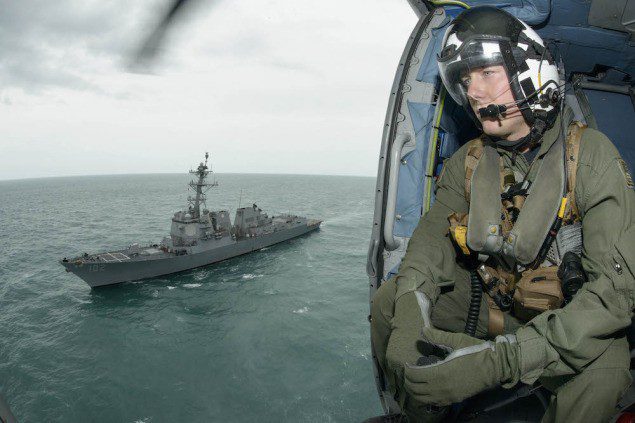 Naval Aircrewman 2nd Class Cody Witherspoon, assigned to Helicopter Maritime Strike Squadron (HSM) 35, keeps a lookout as his helicopter returns to the guided-missile destroyer USS Sampson (DDG 102). Sampson is supporting Indonesian-led search efforts to locate Air Asia Flight QZ8501, January 6, 2015. U.S. Navy photo