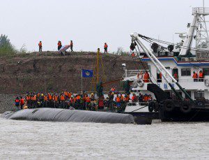 Rescue workers and a capsized ship are seen during a media trip to the site of the sinking, organized by the Chinese goverment, in the Jianli section of Yangtze River, Hubei province