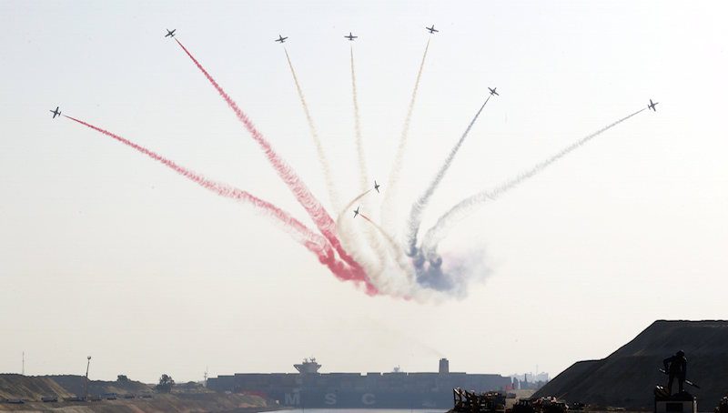 Egyptian air force planes parade in front of cargo container ship crossing new section of the Suez Canal after the opening ceremony of the new Suez Canal, in Ismailia