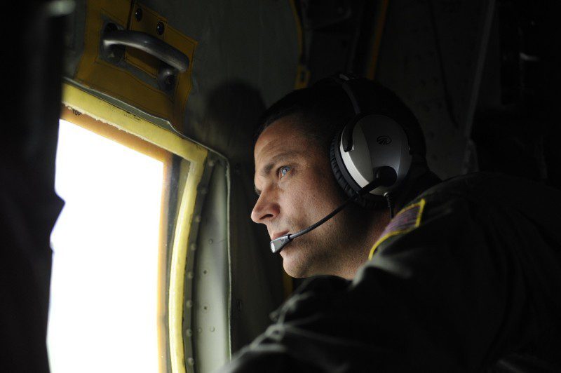 Petty Officer 3rd Class Jimmy Feenstra, an Aviation Machinery Technician from Air Station Elizabeth City, looks through the window of a C-130 aircraft, July 25, 2013, during a training flight. U.S. Coast Guard photo by Petty Officer 3rd Class David Weydert