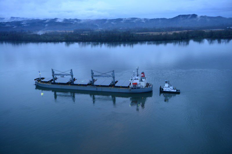 A tug helps stabilize the motor vessel Sparna, a 623-foot Panamanian-flagged bulk carrier, while the Sparna awaits repairs after it sustained damage below the waterline while transiting in the Columbia River near Cathlamet, Wash., March 21, 2016. The Sparna is loaded with grain and was headed west on the Columbia River when the incident occurred. (U.S. Coast Guard photo by Petty Officer 1st Class Levi Read)