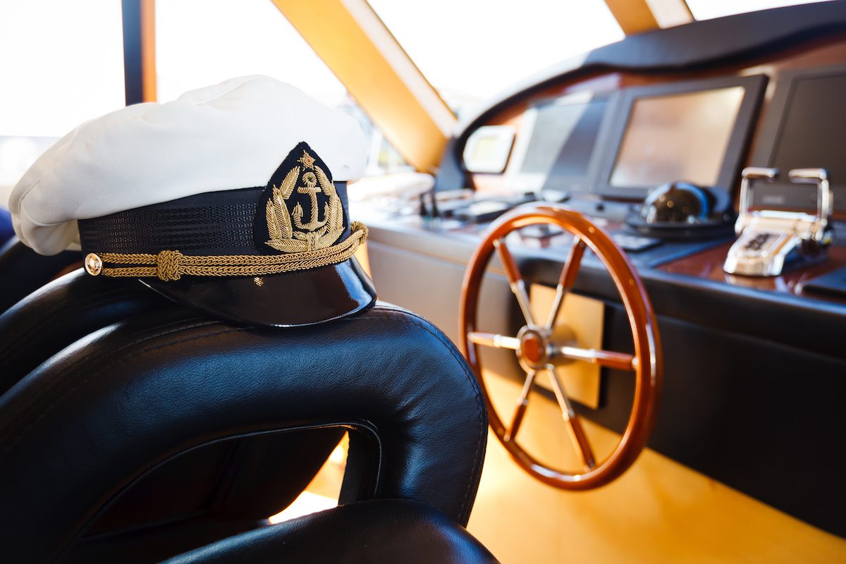 A cptain's Hat sitting on Captain's Chair on the bridge of a yacht