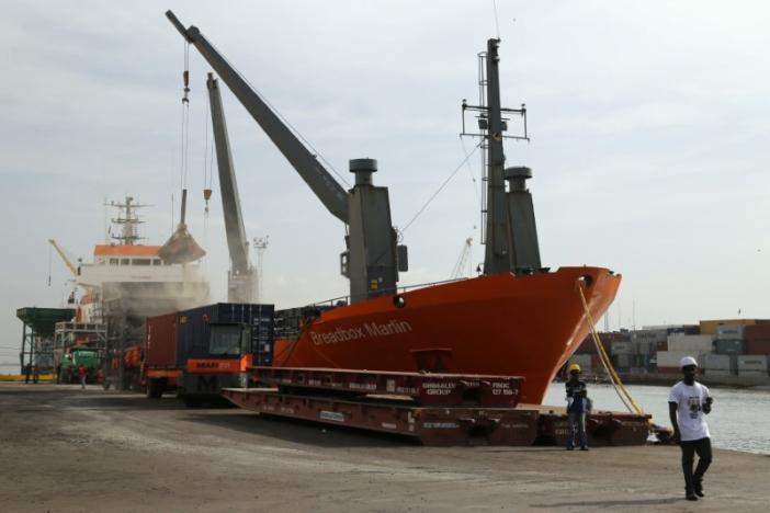 Port workers are seen in front of a shipping vessel unloading its cargo in the port of Banjul