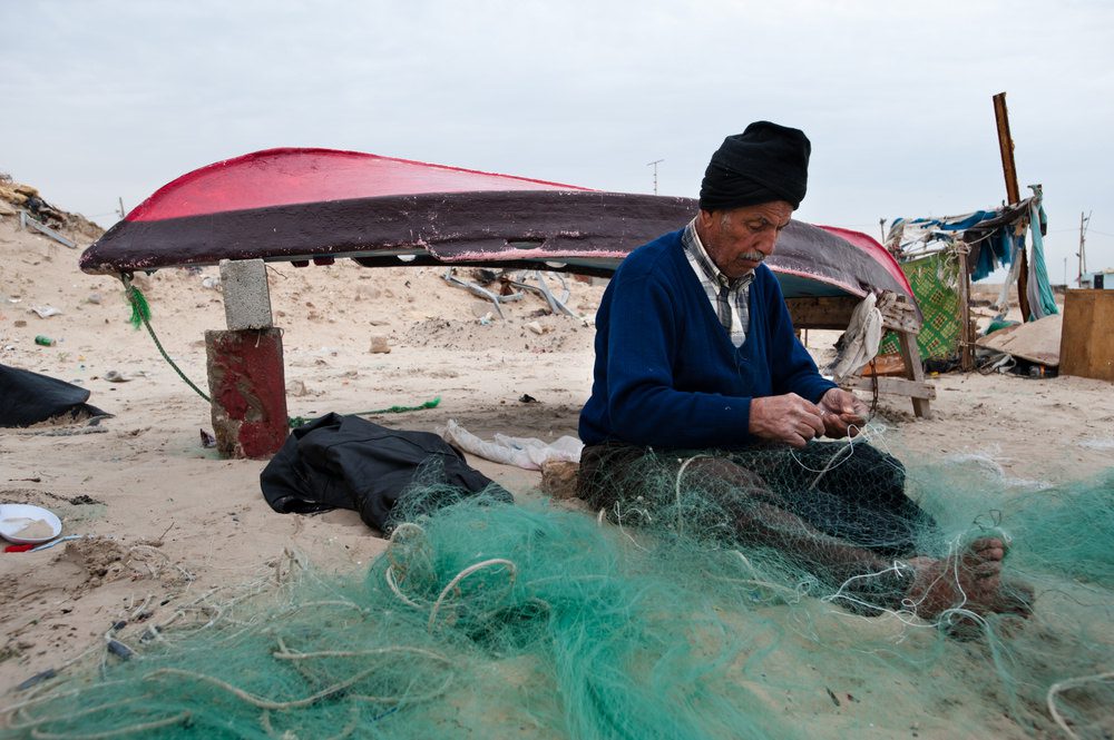 Palestinian fisherman mends his nets