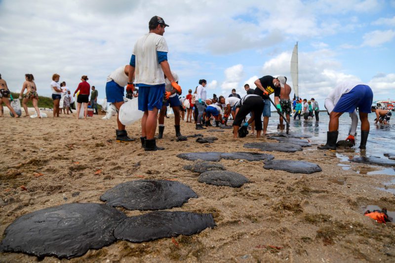 People work to remove an oil spill on Suape beach in Cabo de Santo Agostinho