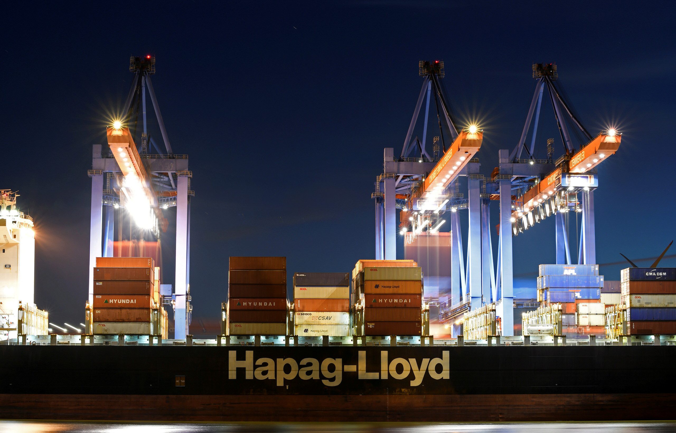 Photo of a hapag-lloyd containership in port with cranes overhead
