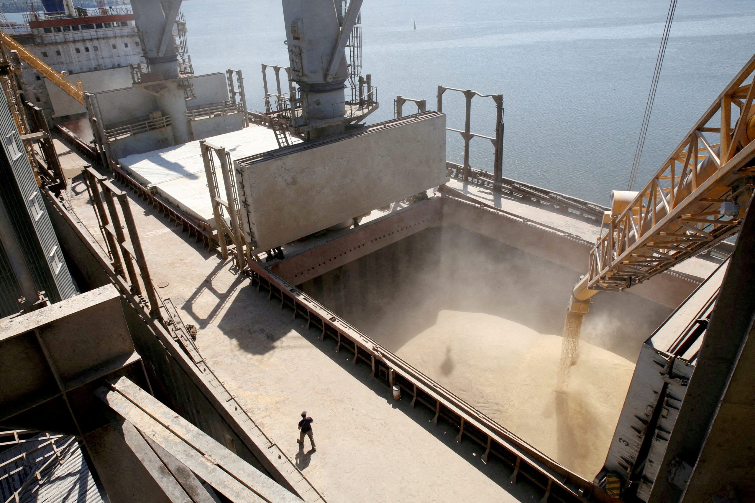 A dockyard worker watches as barley grain is poured into a ship in Nikolaev. REUTERS/Vincent Mundy