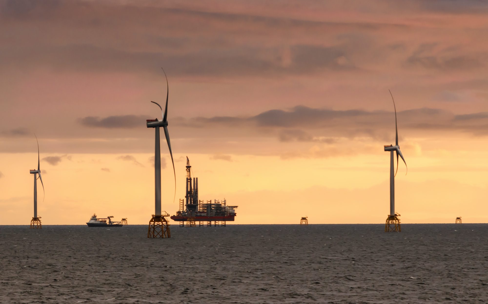 A stock photo of a vessel servicing an offshore wind farm at sunset