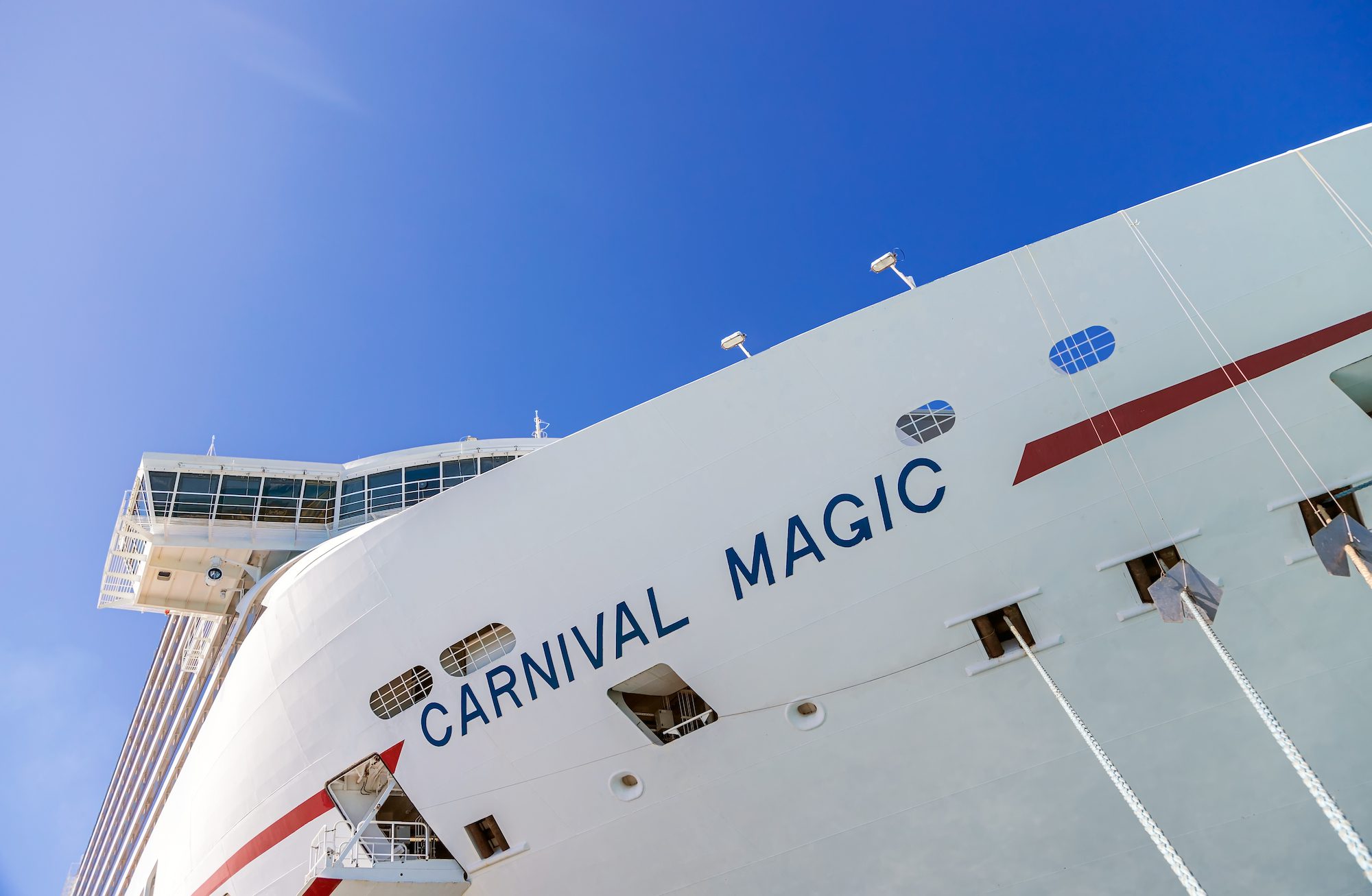 Side view of cruise ship Carnival Magic docked at port Grand Turk on the blue sky background