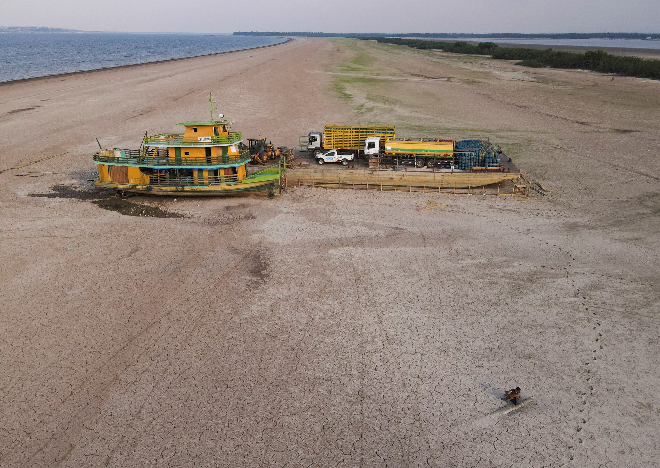 A tug boat and a barge carrying three trucks, 2,000 empty cooking gas cylinders and a backhoe, lie stranded on a sand bank of a diminished Rio Negro river after running aground last month, as the region is hit by a severe drought, in Cacau Pirera, Brazil October 10, 2023. REUTERS/Bruno Kelly