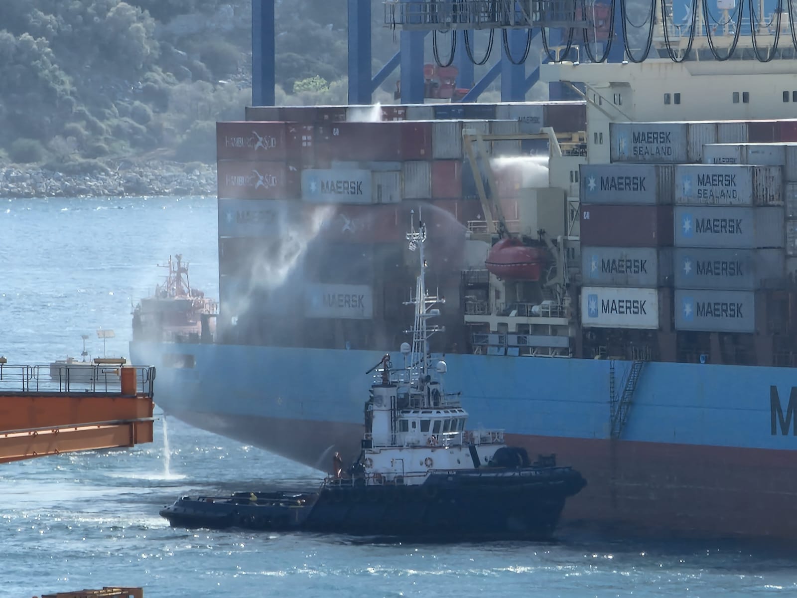 Tugs spray water on a container on board the Luna Maersk.