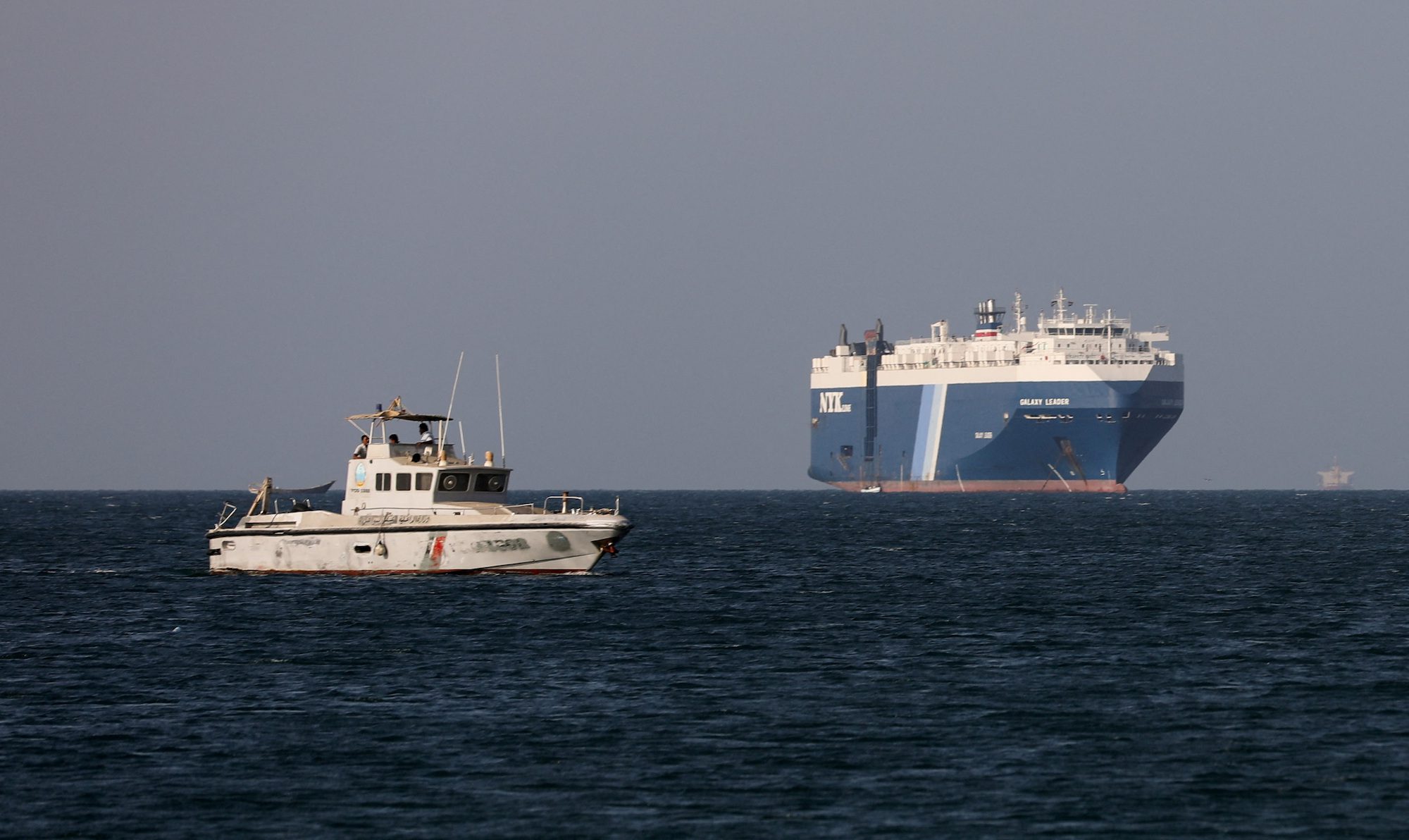 A Yemeni Coast Guard boat sails near the Galaxy Leader commercial ship, seized by Yemen's Houthis last month, off the coast of al-Salif, Yemen, December 5, 2023.