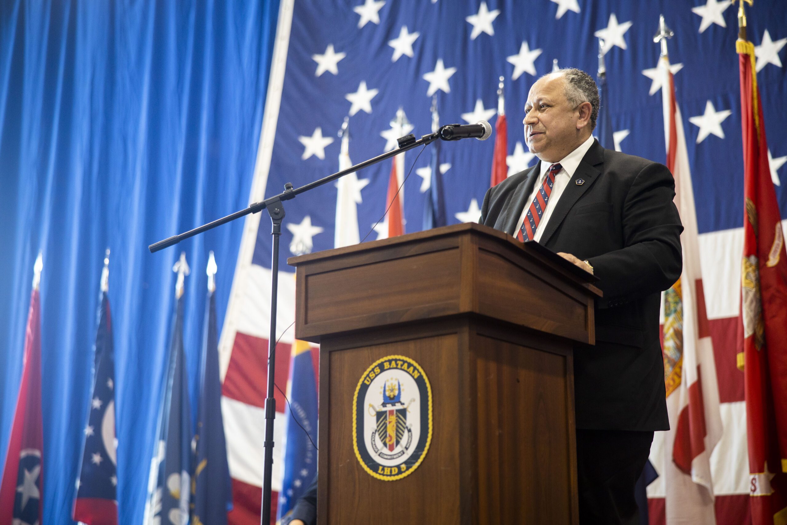 Navy Secretary Del Toro speaking in front of an American flag