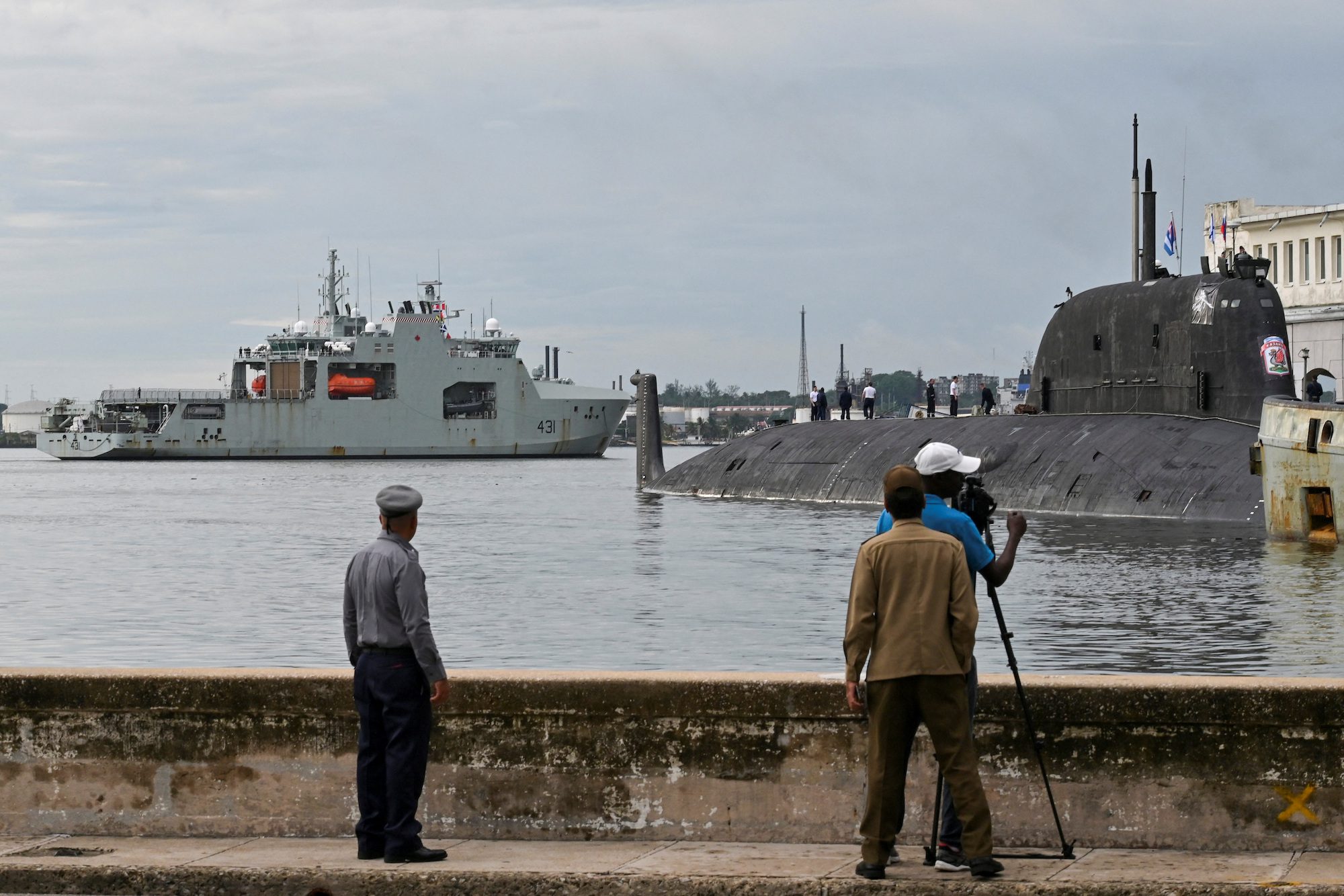 People watch Canadian navy patrol boat HMCS Margaret Brooke passing by Russian nuclear-powered cruise missile submarine Kazan as it enters Havana's bay, Cuba, June 14, 2024. REUTERS/Stringer