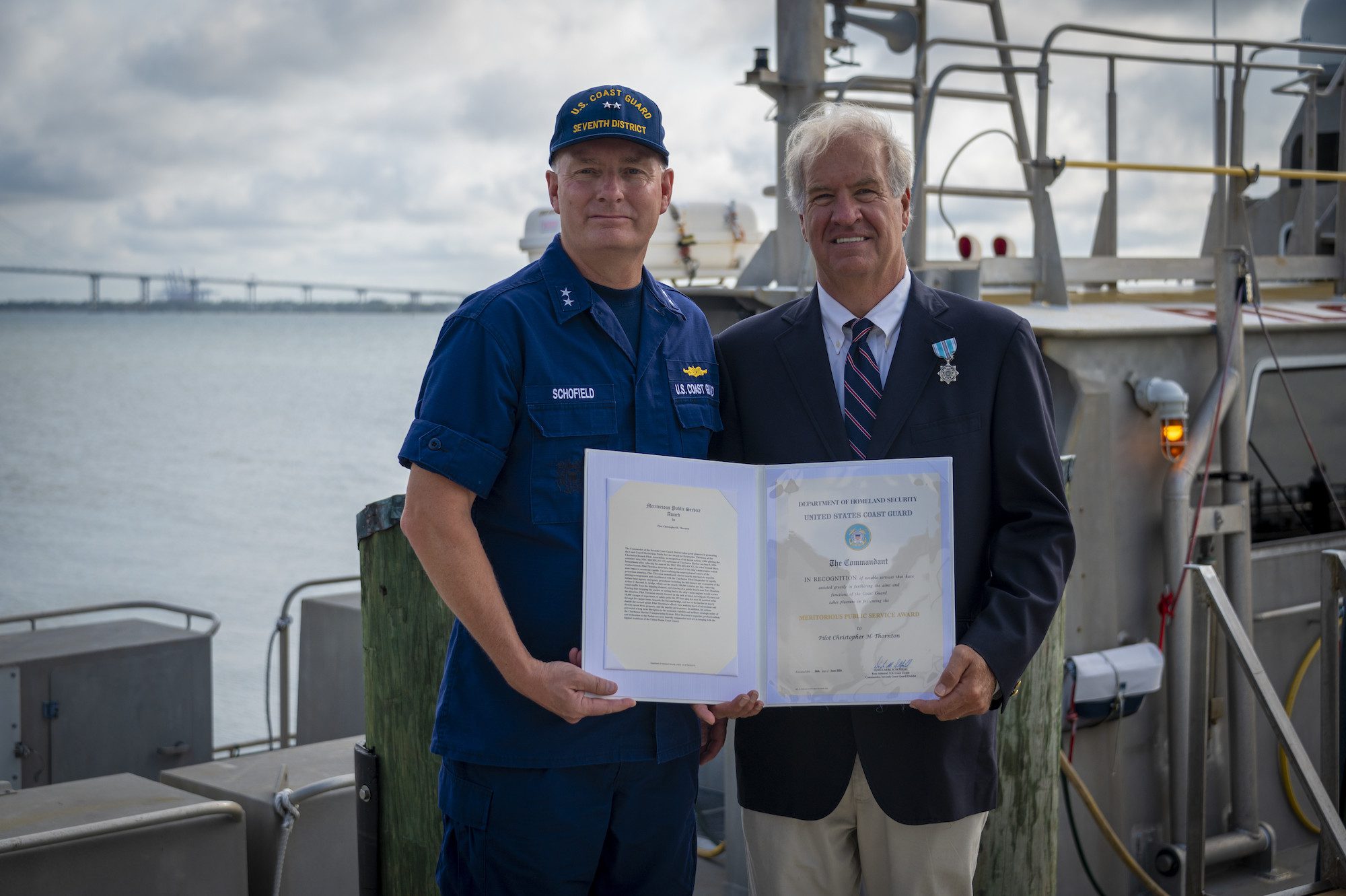 Rear Adm. Douglas Schofield, commander, Coast Guard Seventh District, presents a Meritorious Public Service Award to Christopher Thornton with the Charleston Branch Pilots Association for his commendable actions related to the uncontrolled acceleration of the MSC Michigan VII at the Charleston Branch Pilots Station in Charleston, South Carolina, June 26, 2024. U.S. Coast Guard Photo