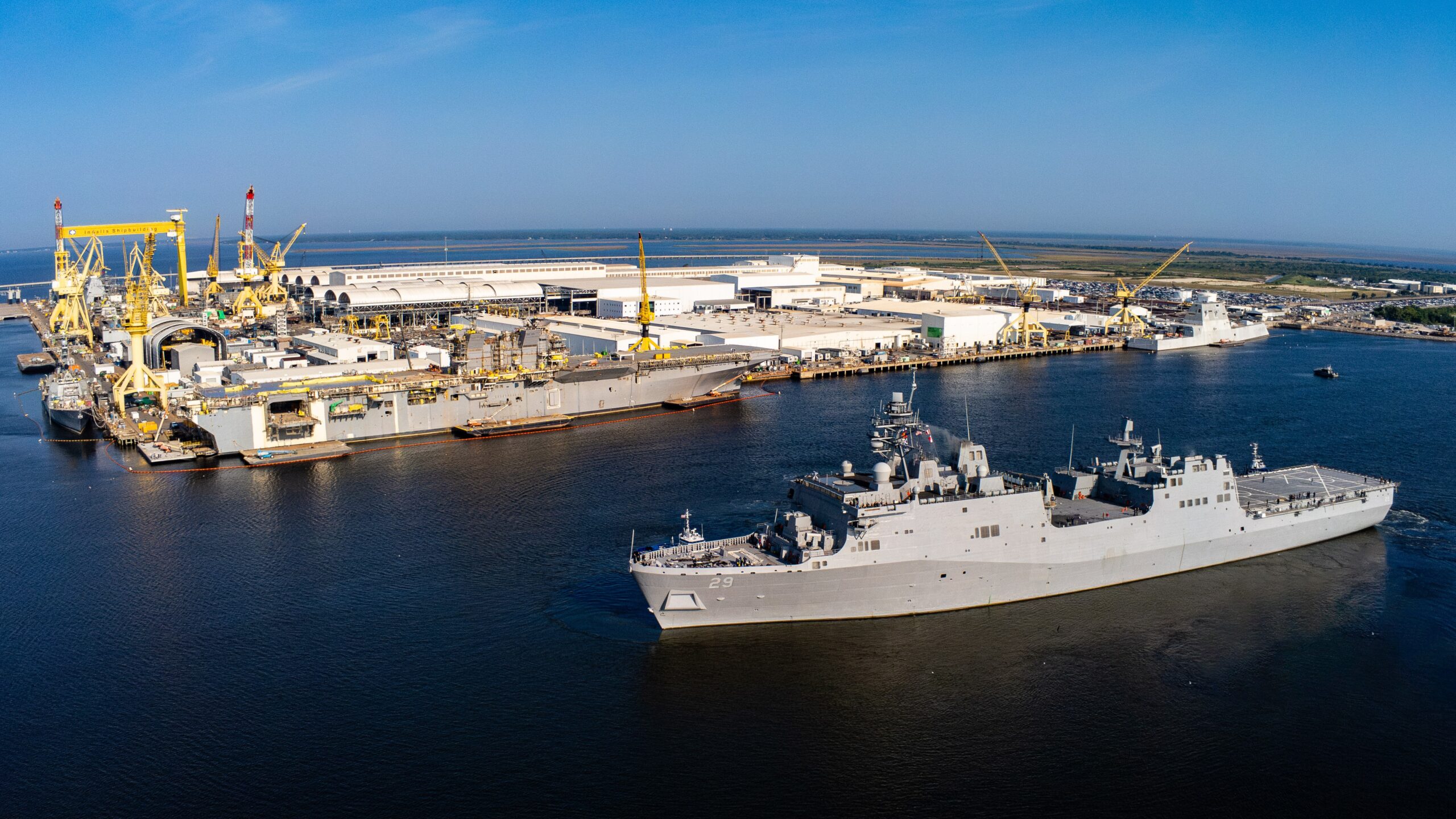 Aerial view of HII’s Ingalls Shipbuilding division taken on Aug. 22, 2024 as USS Richard M. McCool, Jr. (LPD 29) departed from Ingalls to its commissioning site in Pensacola, Florida, while Bougainville (LHA 8) is shown under construction in the background.