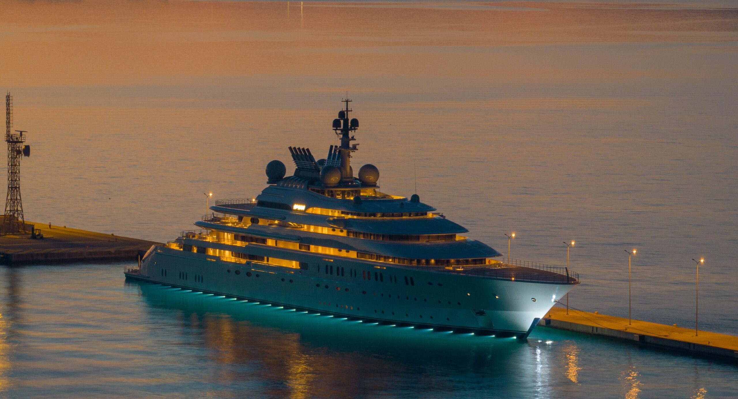Superyacht with deck lights on docked at sunset