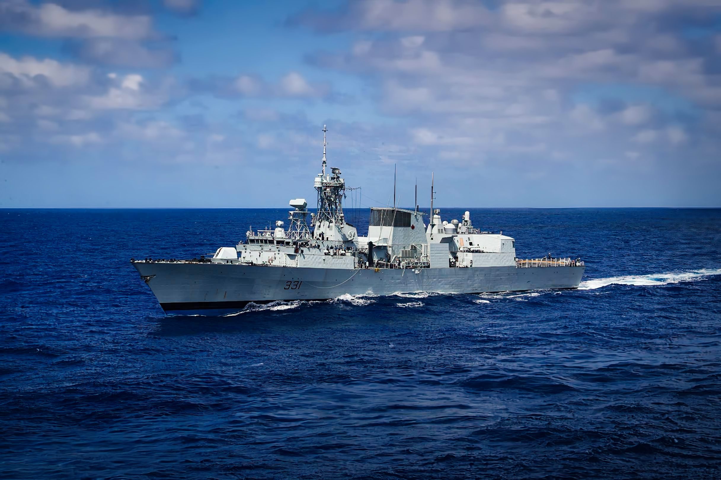 Royal Canadian Navy warship on a light sea with clouds in the background