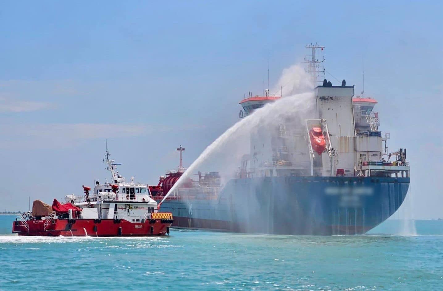 A Singapore Civil Defence Force vessel cools the Med Atlantic in Singapore waters