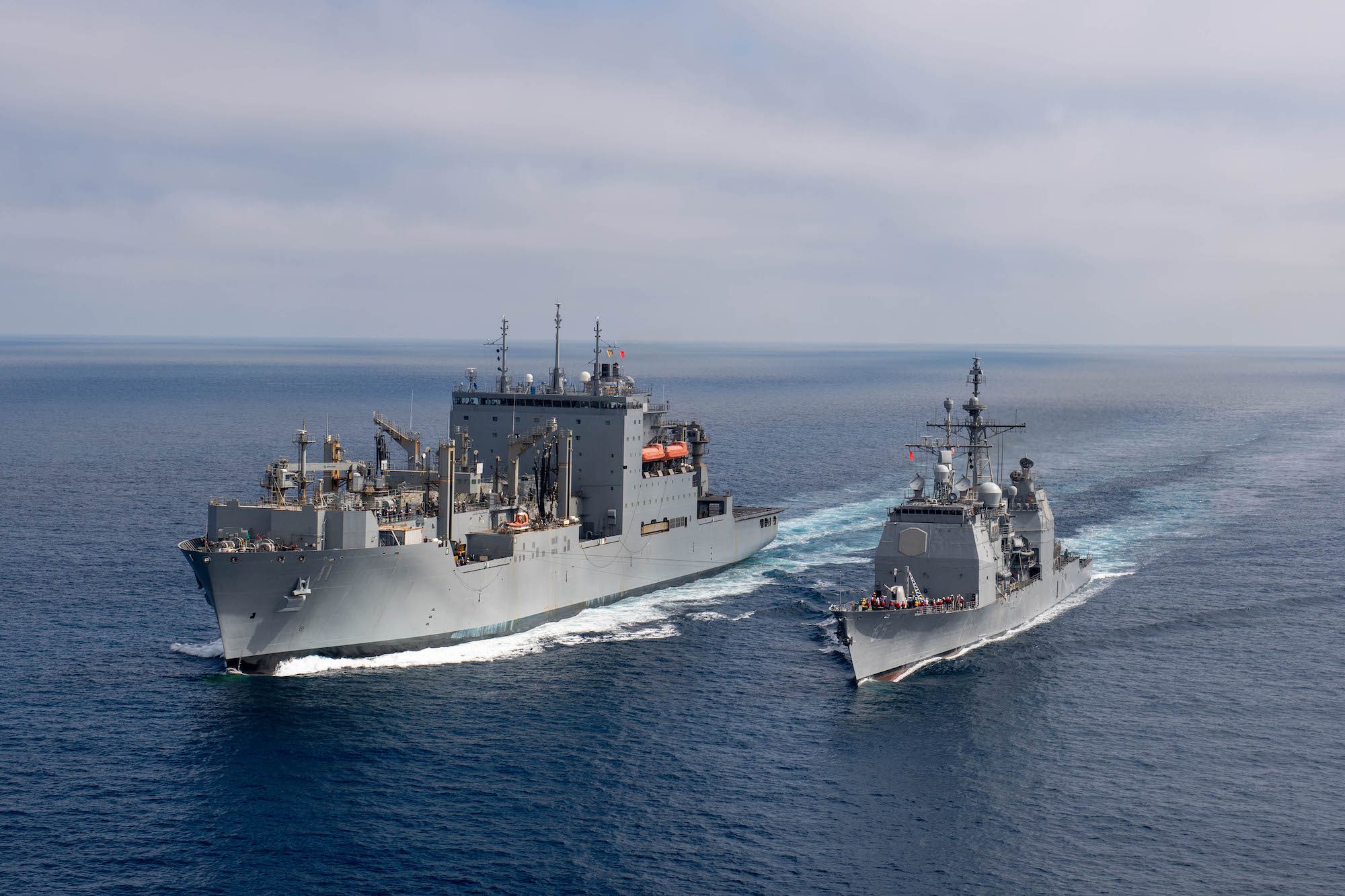 The Ticonderoga-class guided-missile cruiser USS Chosin (CG 65) steams alongside the Lewis and Clark-class dry cargo ship USNS Washington Chambers (T-AKE 11) during an at-sea demonstration of the Transferrable Reload At-sea Method (TRAM) while underway in the Pacific Ocean Oct. 11, 2024.