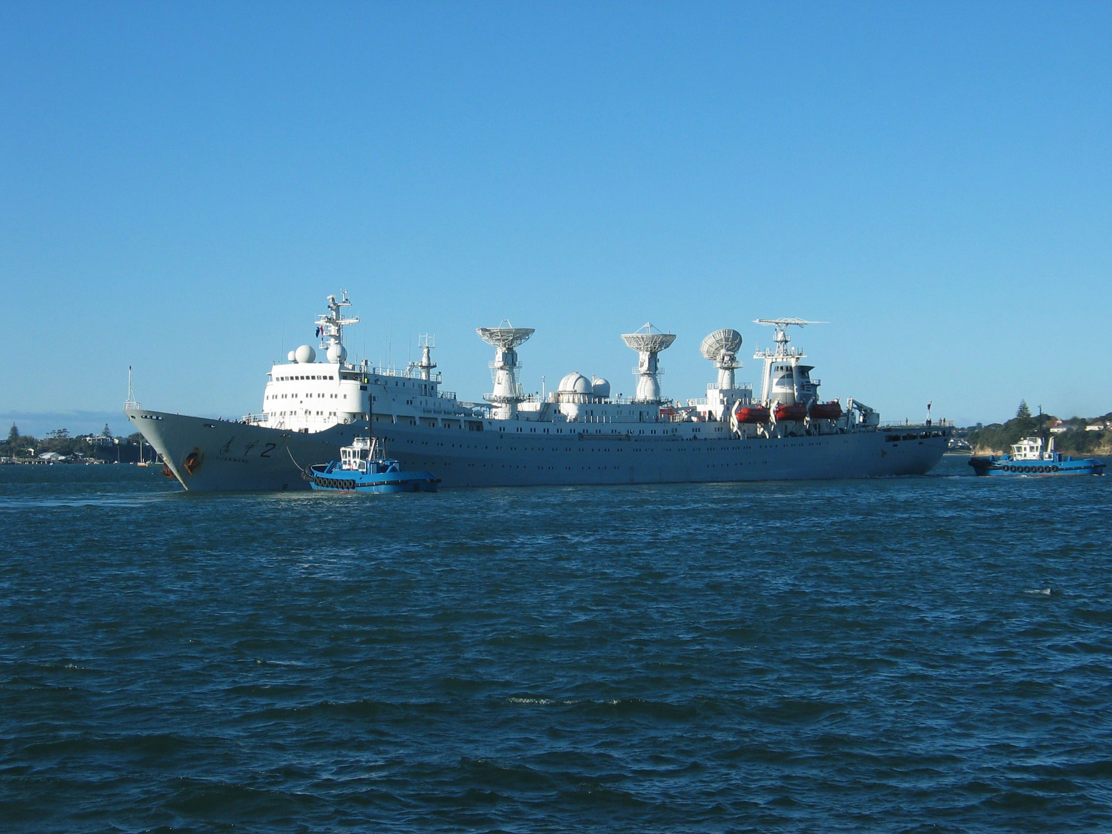 China Navy missile tracking ship leaving port with a tugboat