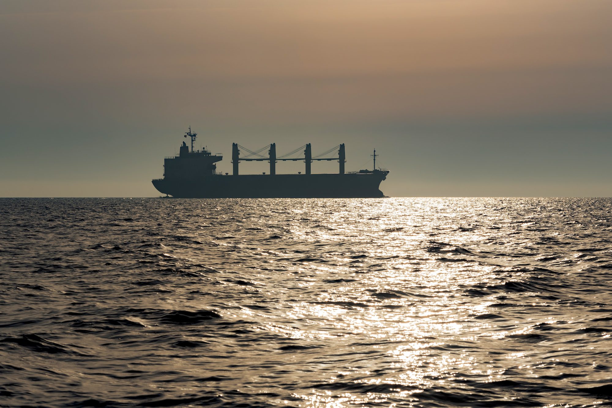 General cargo ship on the horizon at sunset