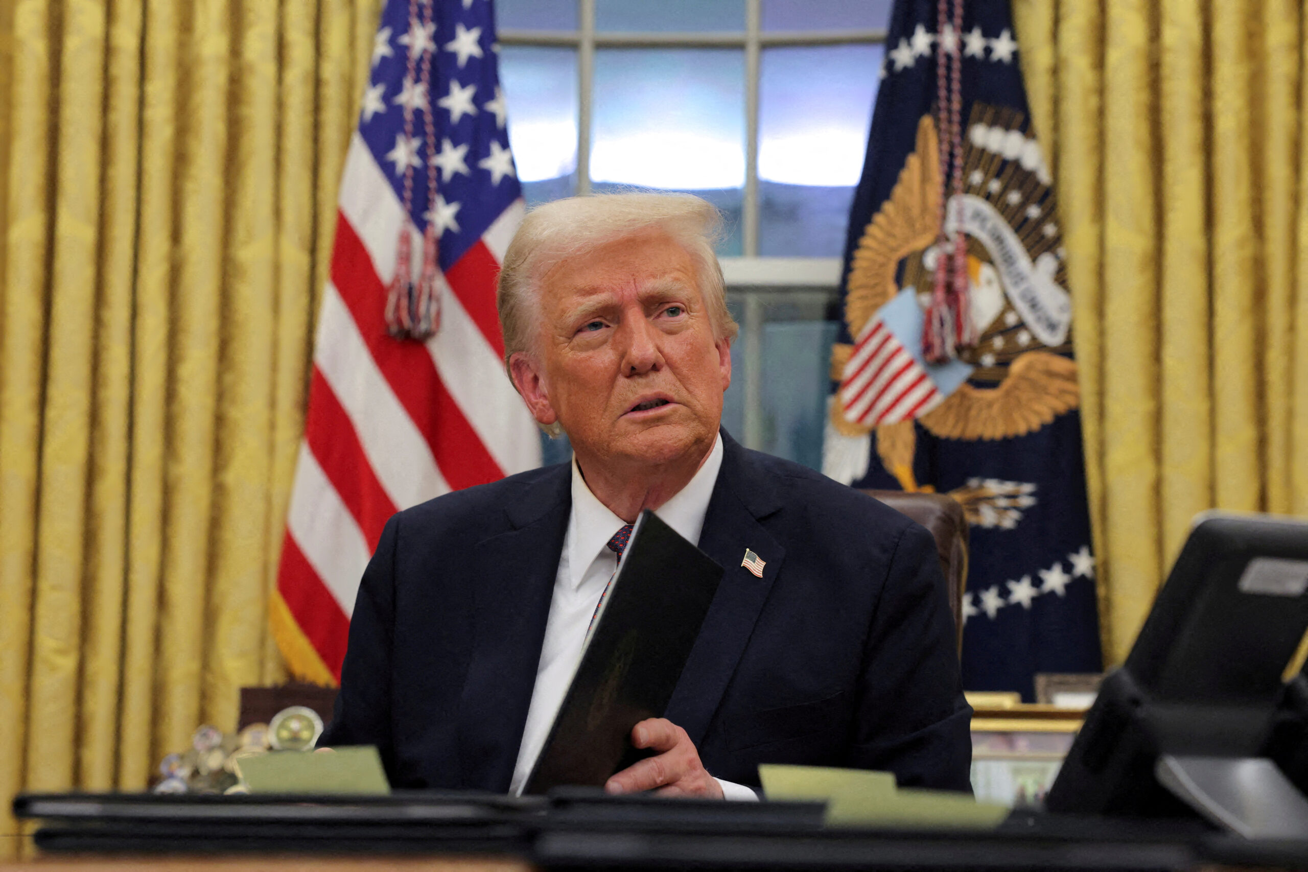 FILE PHOTO: U.S. President Donald Trump signs documents as he issues executive orders and pardons for January 6 defendants in the Oval Office at the White House on Inauguration Day in Washington