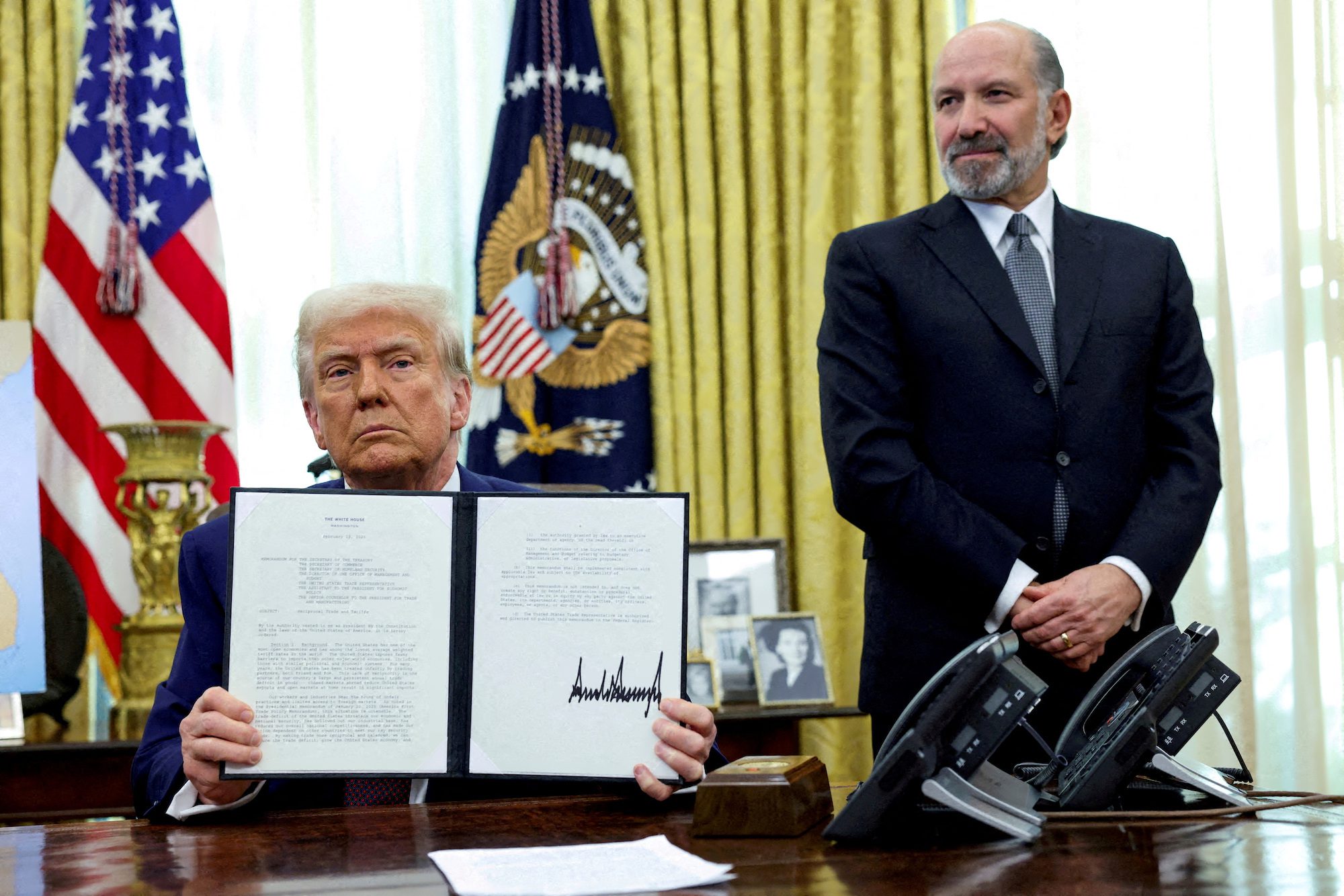 FILE PHOTO: U.S. President Donald Trump holds an executive order about tariffs increase, flanked by U.S. Commerce Secretary Howard Lutnick, in the Oval Office of the White House in Washington, D.C., U.S., February 13, 2025. REUTERS/File Photo