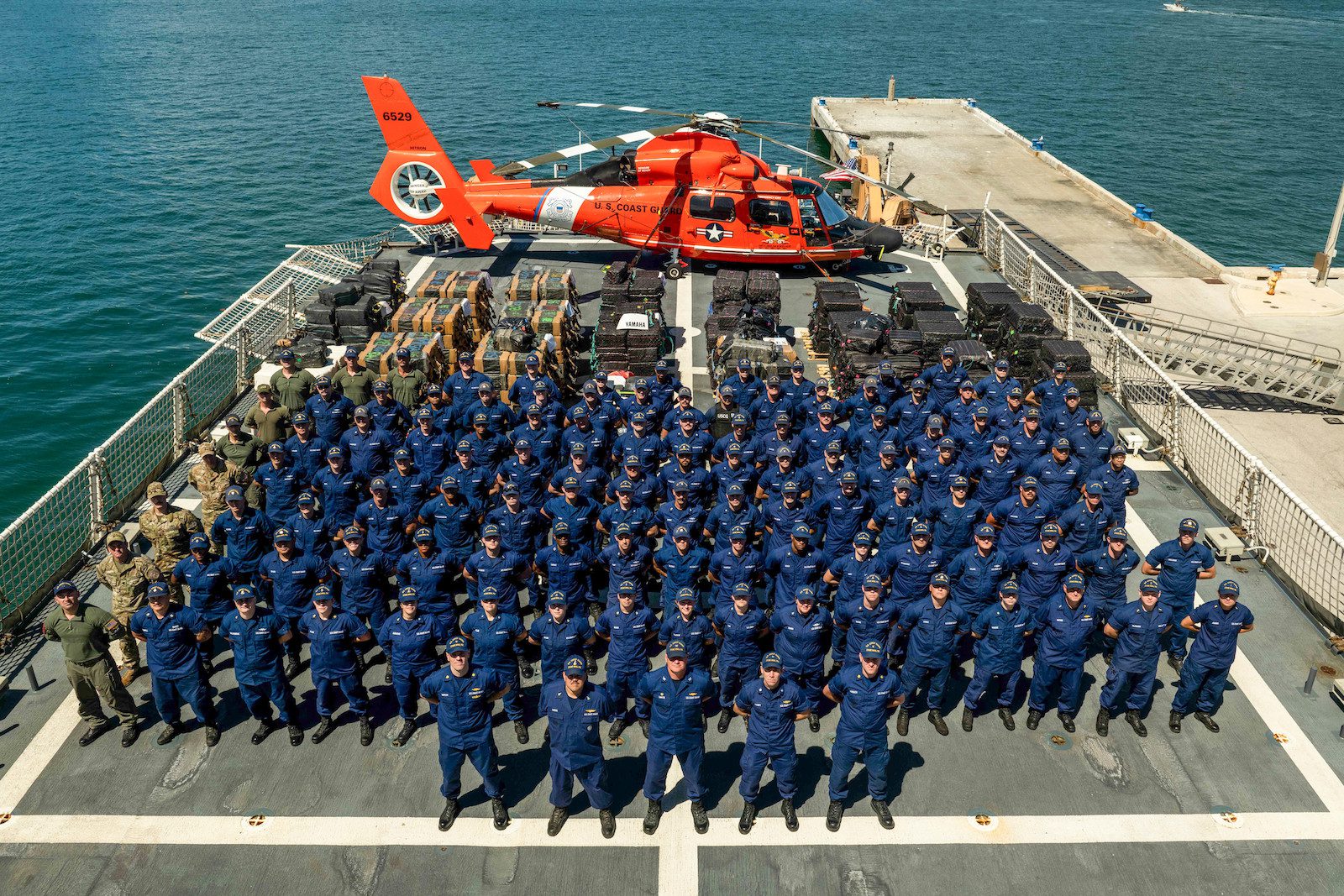 Crew members from USCGC Stone (WMSL-758) stand at parade rest in front of interdicted narcotics at Port Everglades