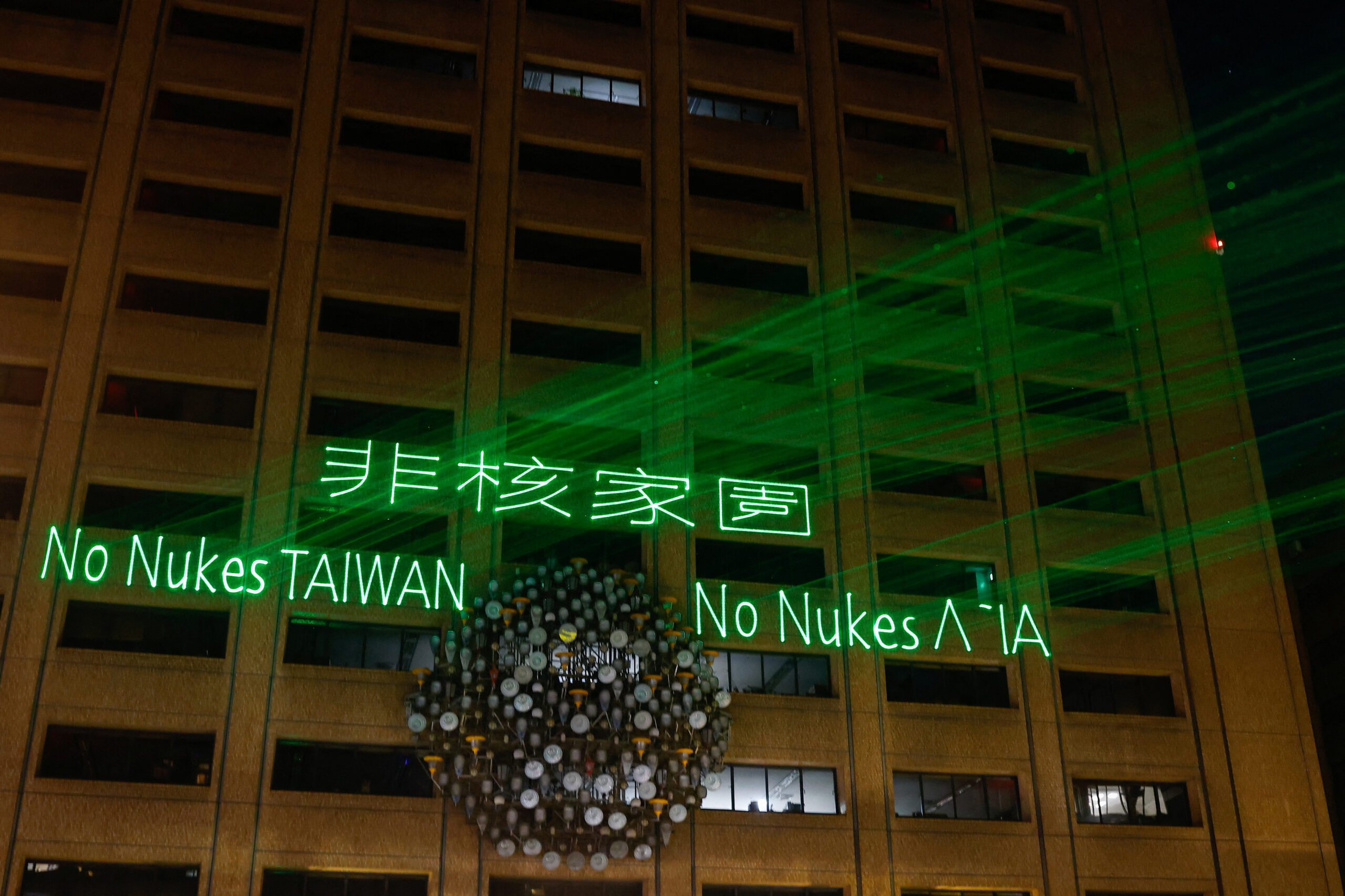 A slogan is displayed on a building, using laser light, as Taiwan shuts down its last Nuclear reactor, in Taipei