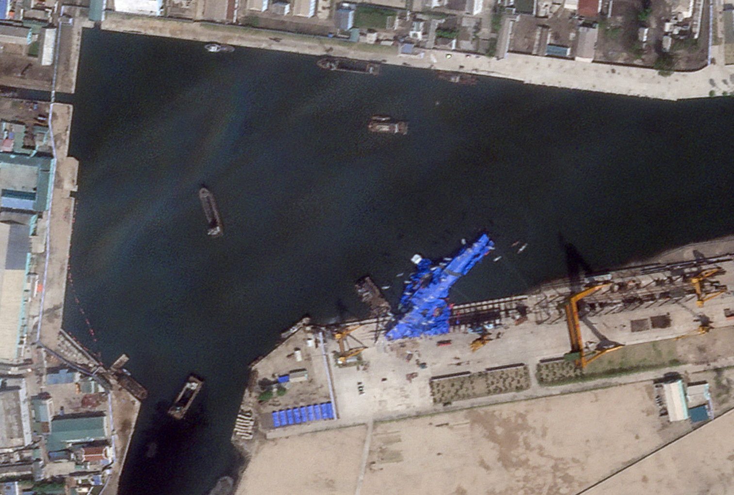 A satellite image shows a North Korean warship covered with a blue tarp after an accident that occurred during its launch at the shipyard in Chongjin