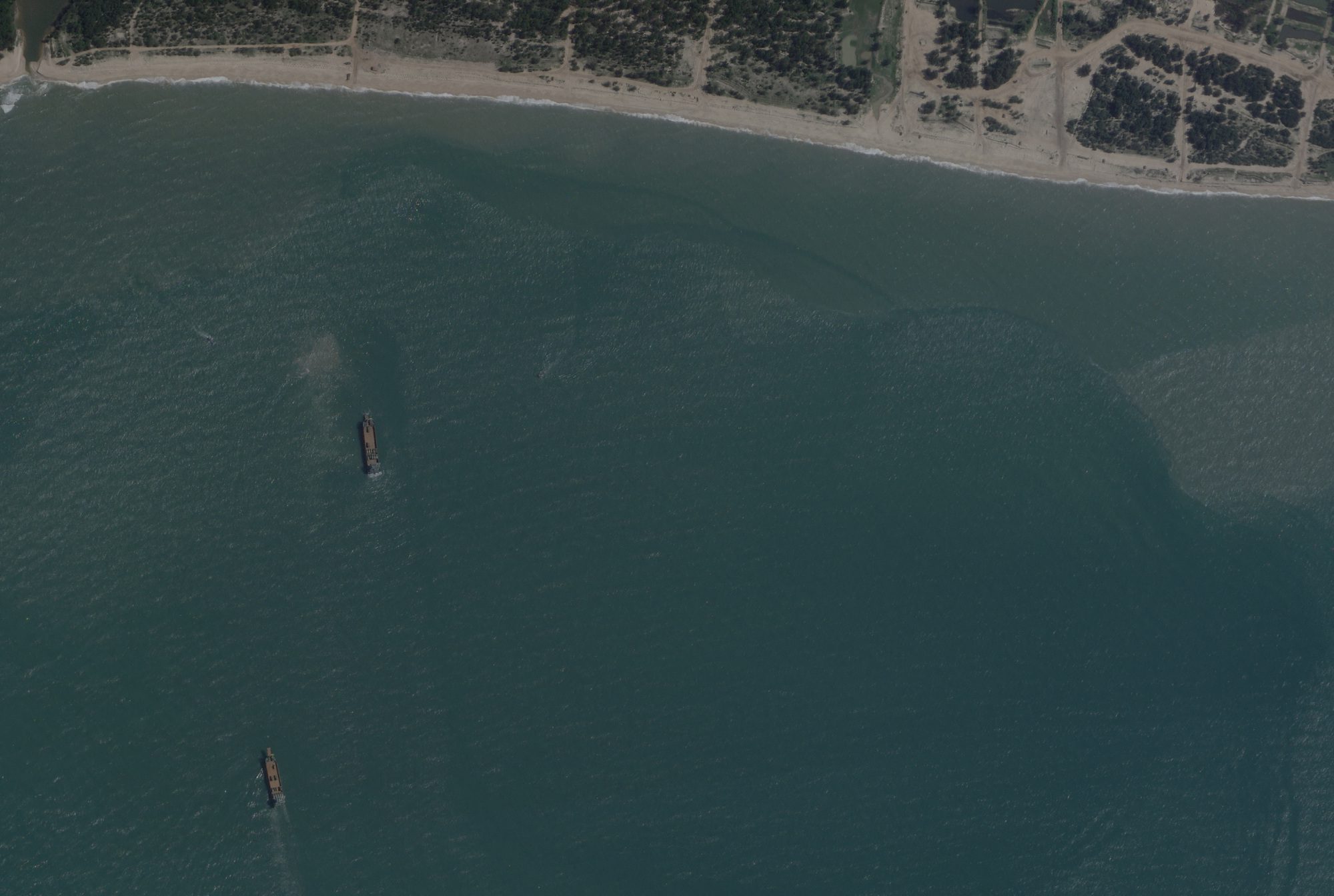 FILE PHOTO: A satellite image taken by Planet Labs shows deck cargo ships, loaded with vehicles, cruising towards the beach near Jiesheng, Guangdong, China