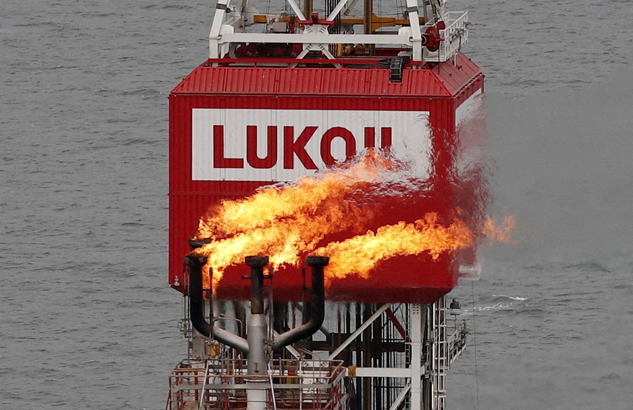 A gas torch is seen next to the Lukoil company sign at the Filanovskogo oil platform in the Caspian Sea, Russia October 16, 2018. Picture taken October 16, 2018. REUTERS/Maxim Shemetov