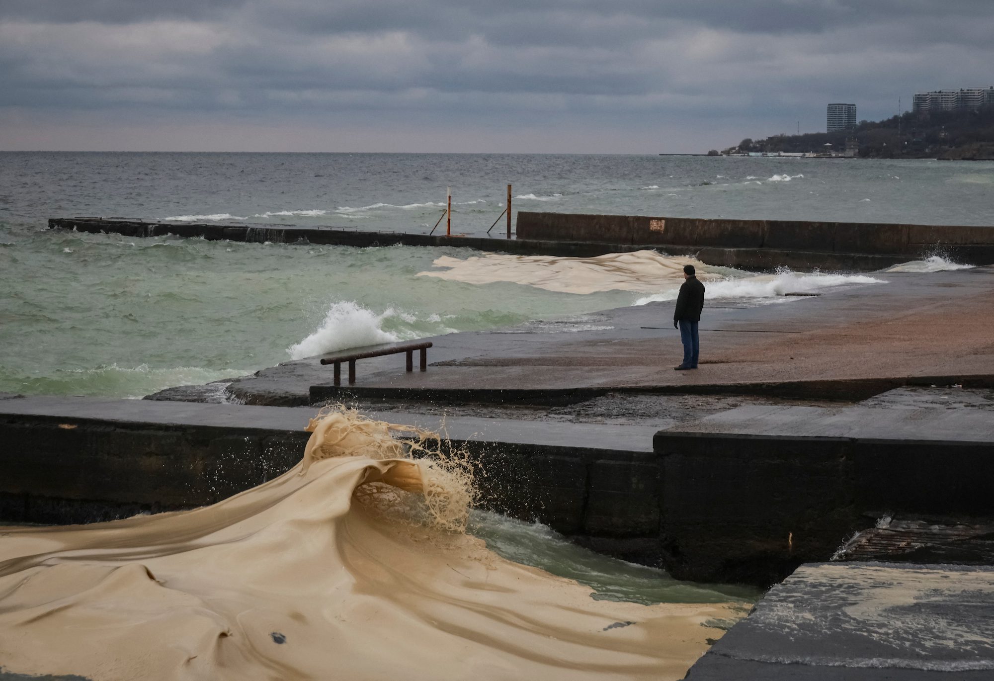 A resident stands at an embankment near a sunflower oil spill from a port terminal that was hit by recent Russian missile and drone attacks