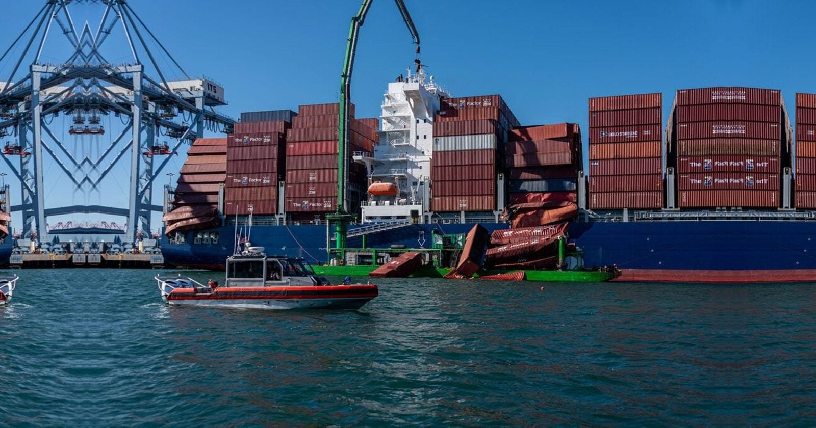 Container ship alongside port cranes with several collapsed shipping containers; small pilot boat in foreground.