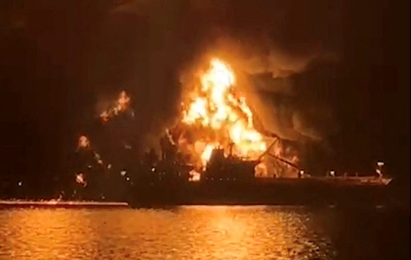 A ship is illuminated by fire from a burning vessel, after Iranian explosive-laden boats appear to have attacked two fuel tankers in Iraqi waters setting them ablaze, according to port, maritime security and risk firms, amid the U.S.-Israeli conflict with Iran, in this screengrab taken from a handout video released March 12, 2026