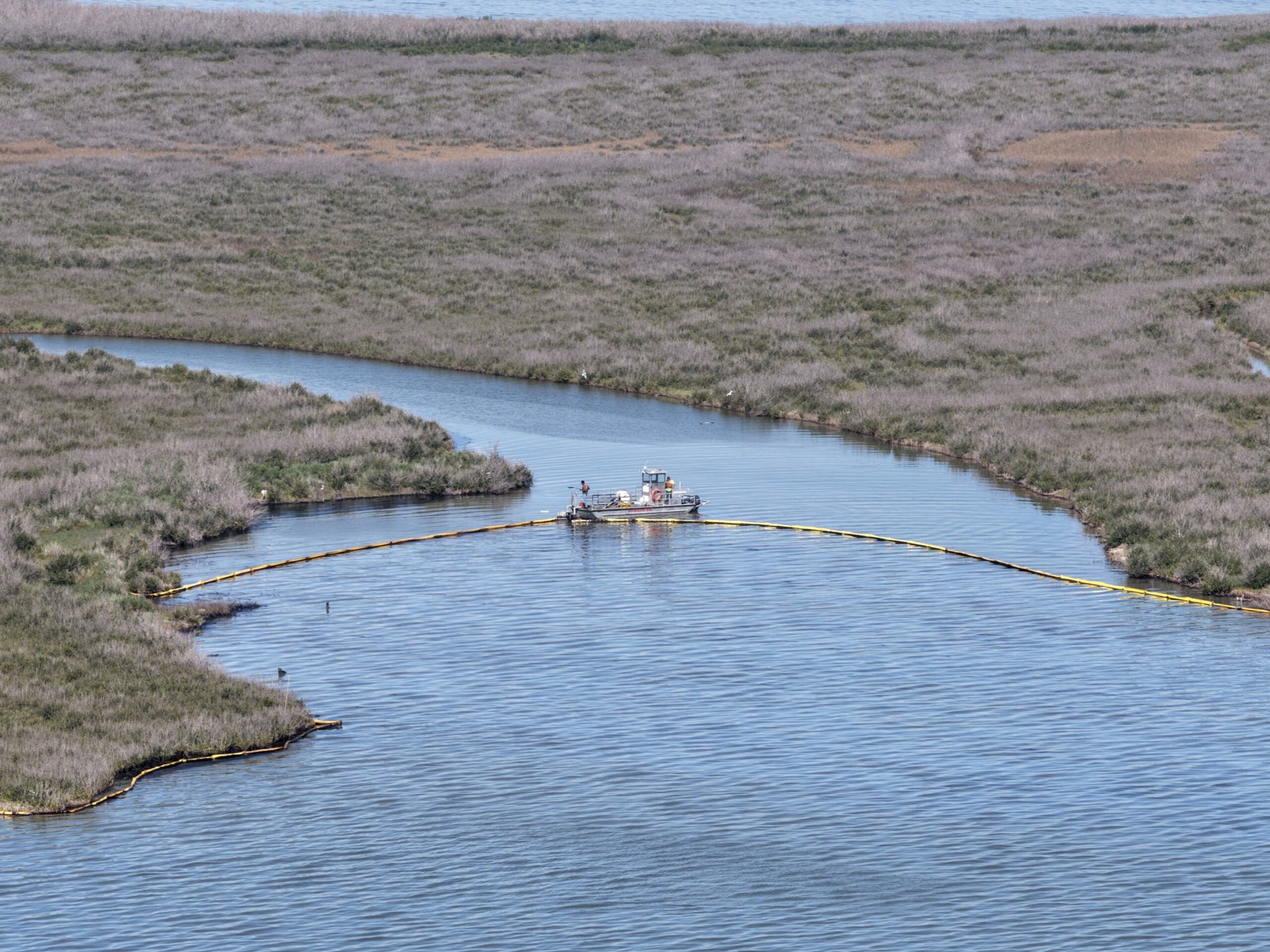 An oil spill vessel maneuvers boom in a marsh following an oil spill from the LOOP