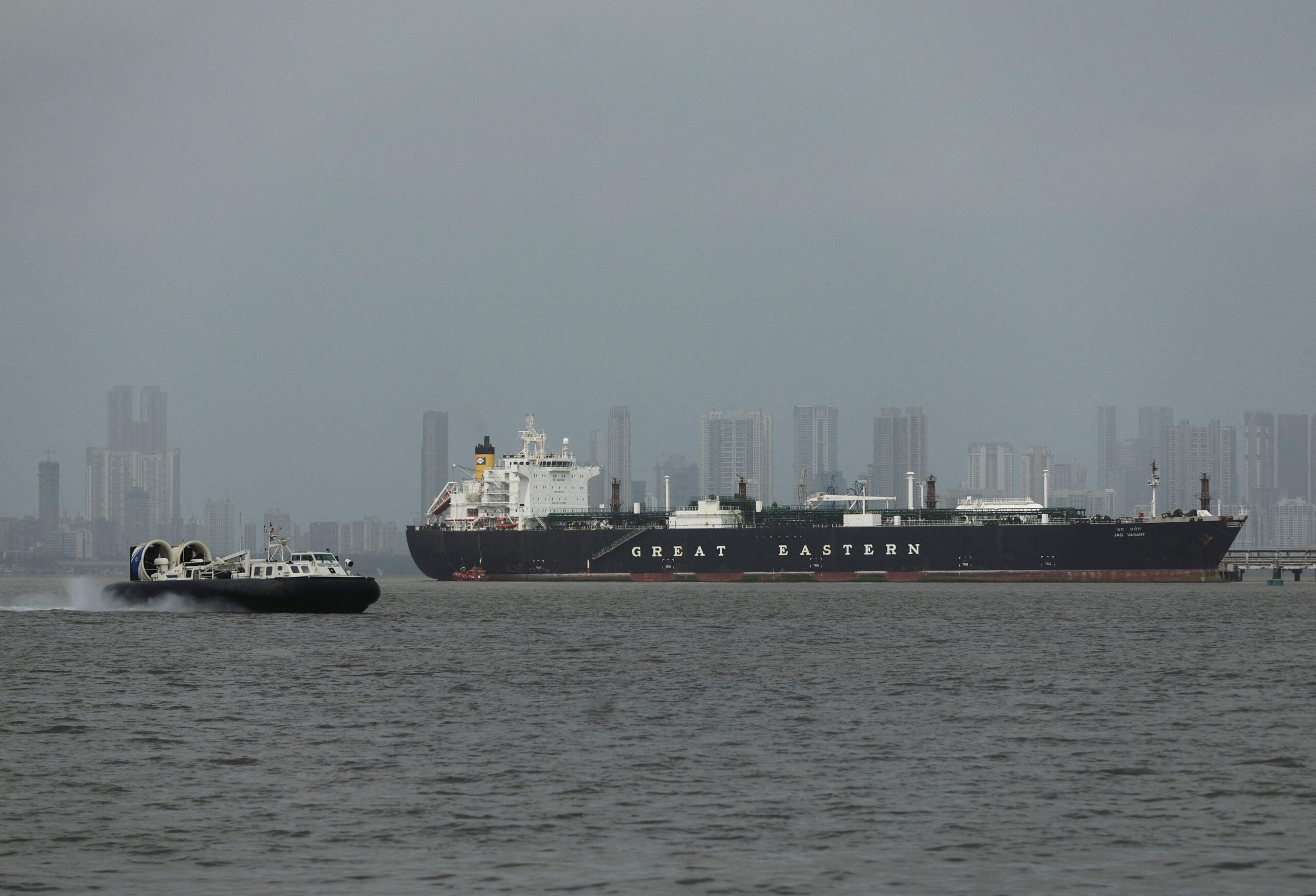 A hovercraft moves past the Jag Vasant vessel transferring LPG at a port after transiting the Strait of Hormuz amid supply disruptions linked to the U.S-Israeli conflict with Iran, in Mumbai