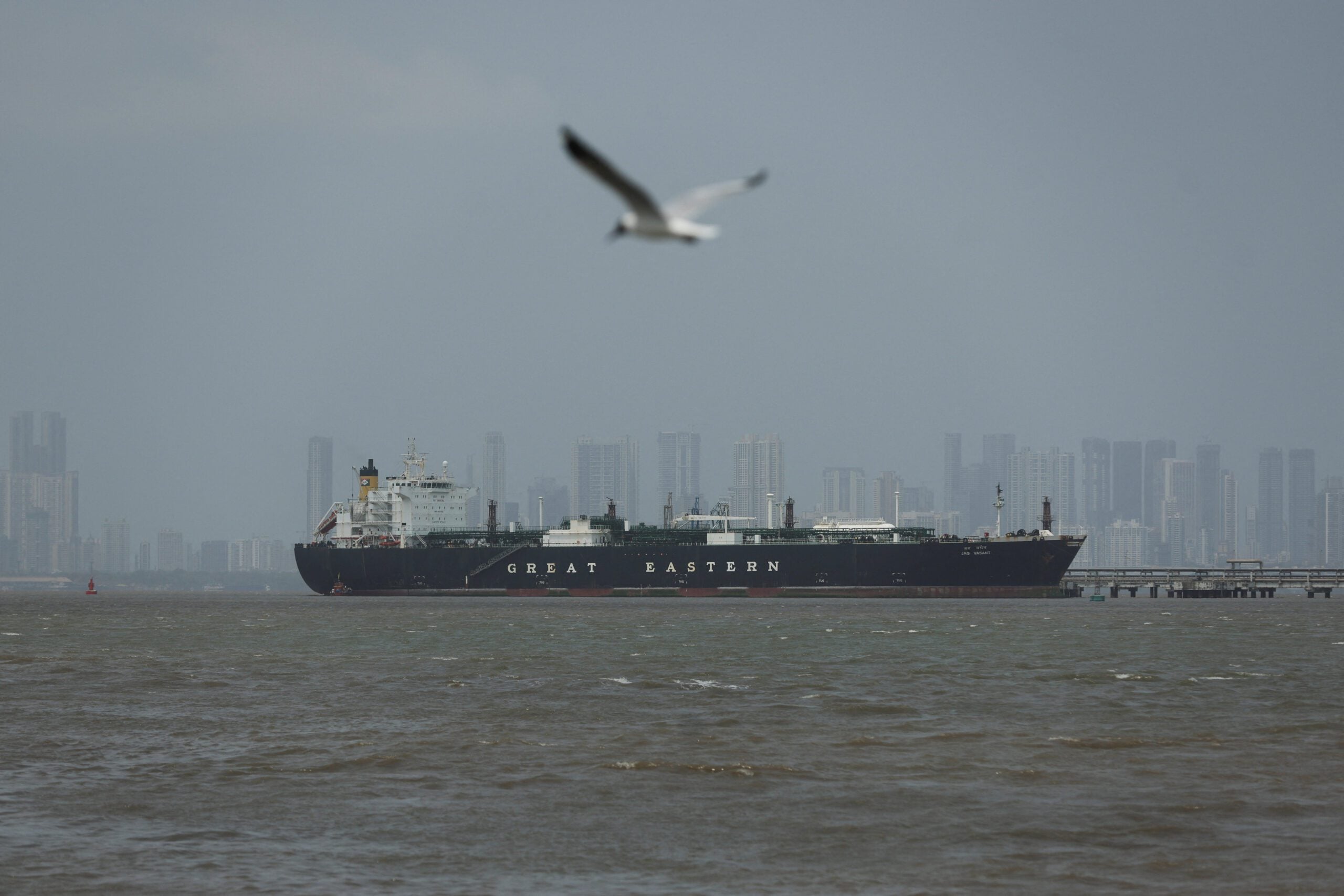 A bird flies near the Jag Vasant vessel transferring LPG at a port after transiting the Strait of Hormuz amid supply disruptions linked to the U.S-Israeli conflict with Iran, in Mumbai