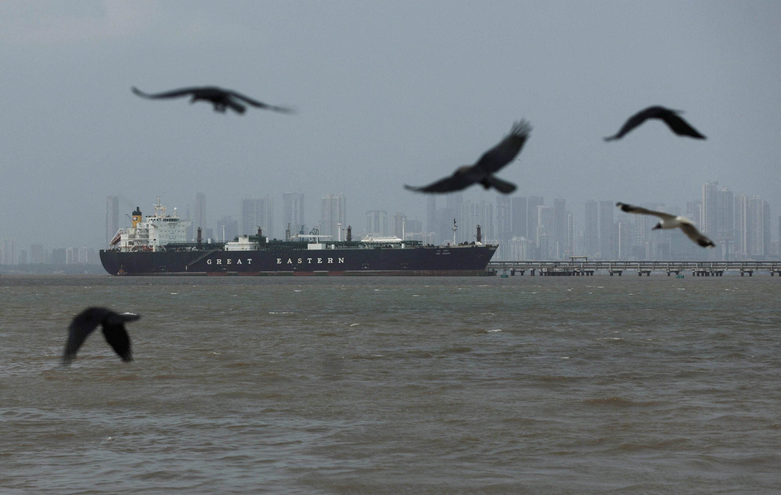 Birds fly near the Jag Vasant vessel transferring LPG at a port after transiting the Strait of Hormuz amid supply disruptions linked to the U.S-Israeli conflict with Iran, in Mumbai