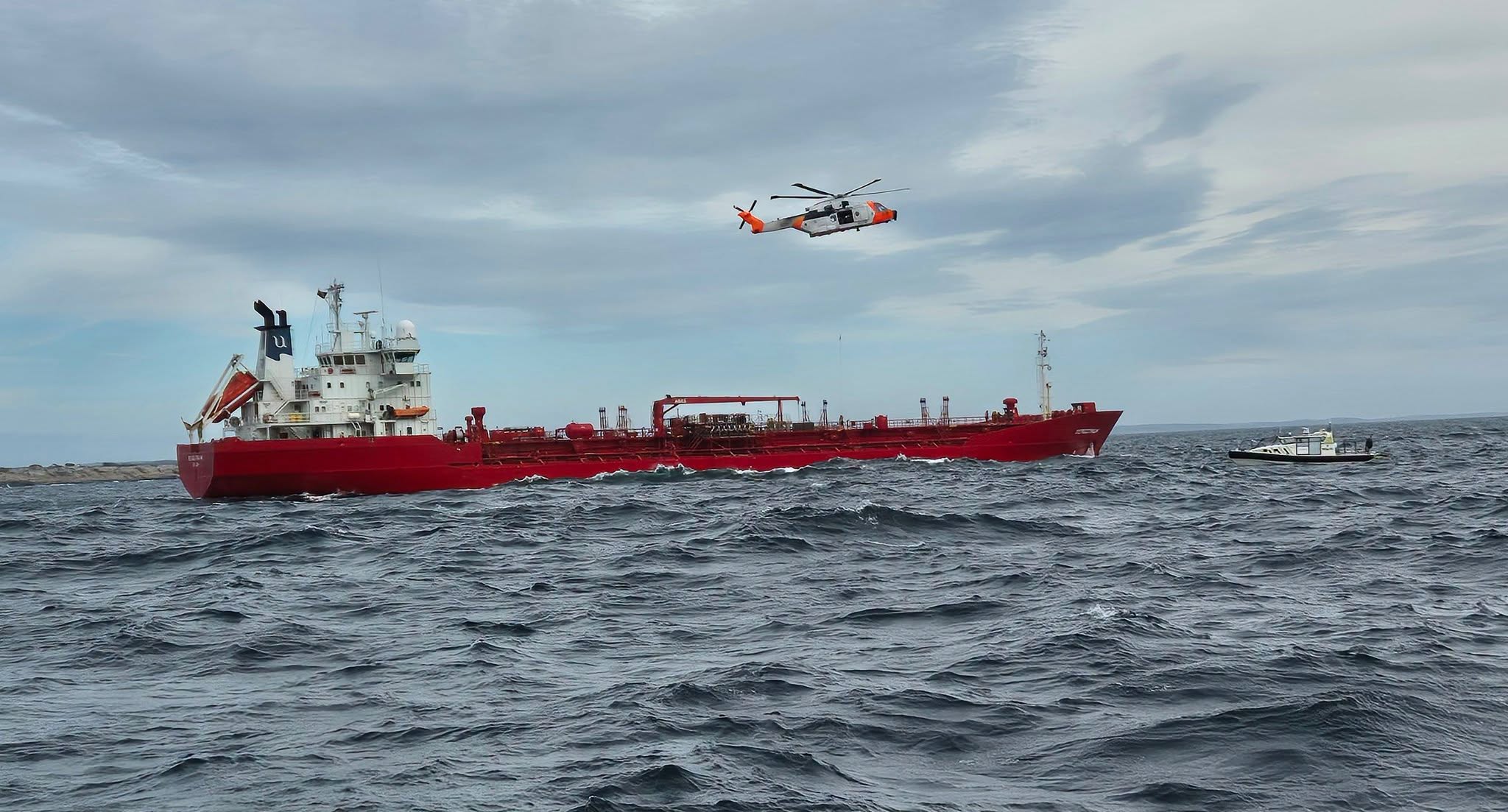 Norwegian chemical tanker Bergstraum at sea with a rescue helicopter hovering overhead and an emergency response boat nearby following an onboard fire off Skjærhalden, Norway.
