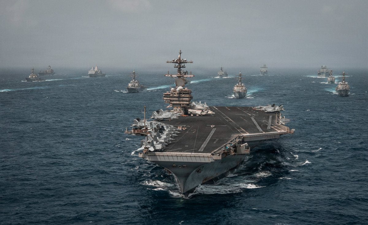 A U.S. Navy aircraft carrier leads a formation of destroyers, cruisers and other warships underway at sea during Middle East operations supporting the renewed U.S. maritime blockade of Iran.