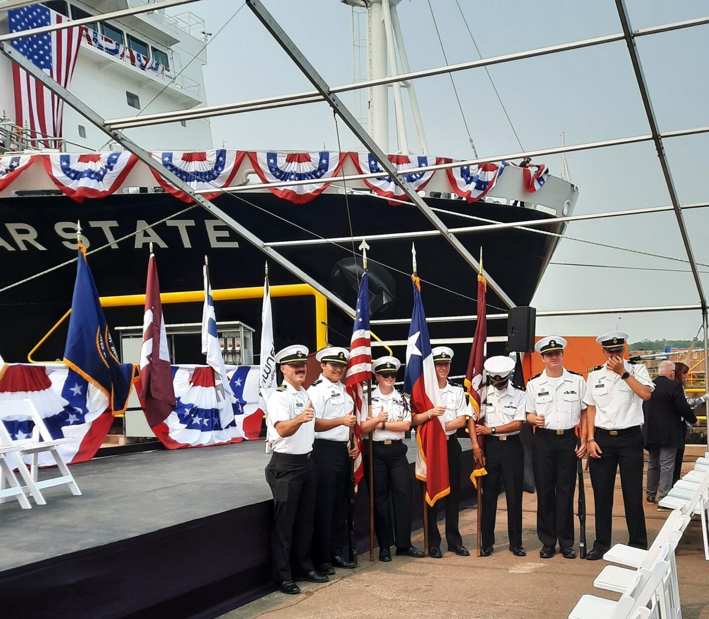Texas A&M Maritime Academy cadets stand with academy and U.S. flags in front of the newly christened training ship TS Lone Star State at Hanwha Philly Shipyard in Philadelphia, decorated for the July 17, 2026 christening ceremony.