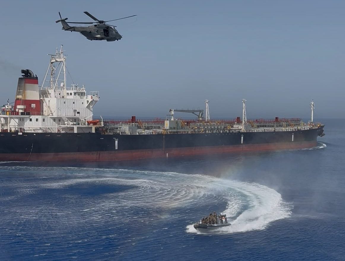 An Operation IRINI helicopter hovers over the tanker SOUTH STAR as a rigid-hull inflatable boat carrying a boarding team approaches the vessel during a flag-verification inspection in the Mediterranean.