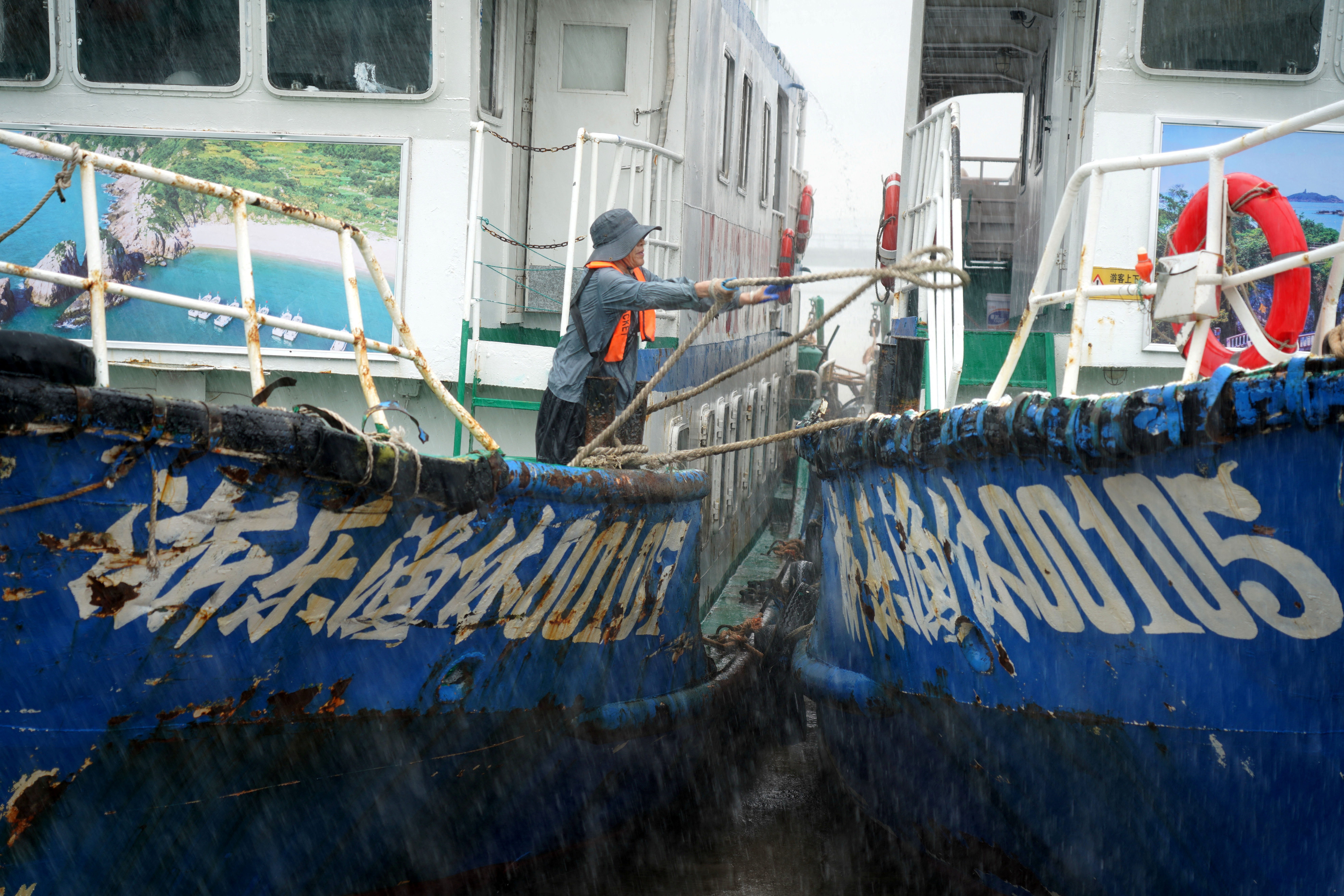 Crew member secures boats at Nanyue Pier as Typhoon Dolphin approaches, in Yueqing Bay.